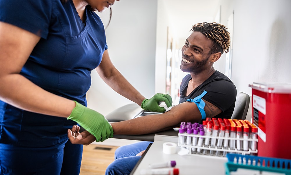 female nurse drawing blood sample from young man in medical office