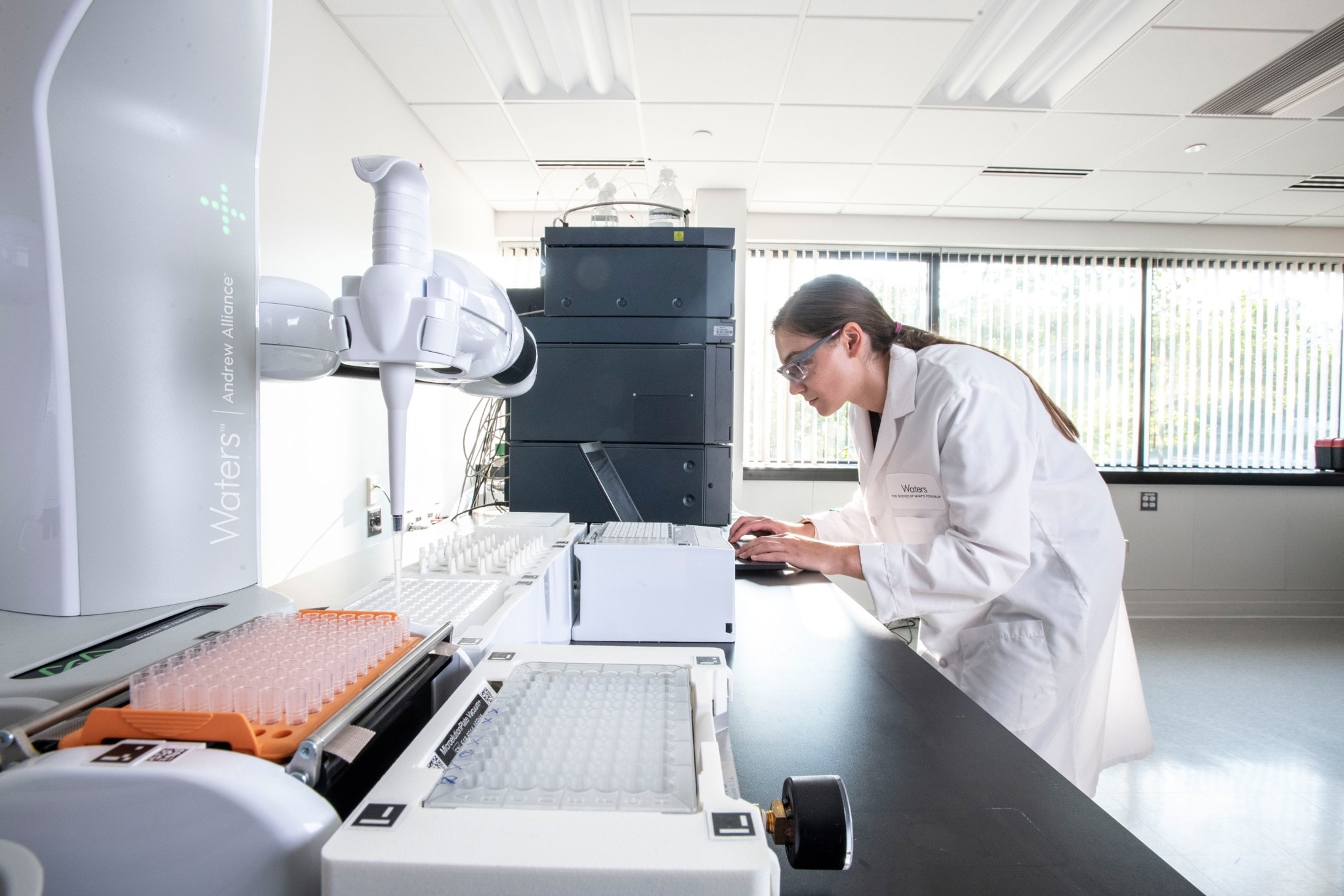 A scientist using a laptop in a laboratory next to an Andrew+ Pipetting Robot