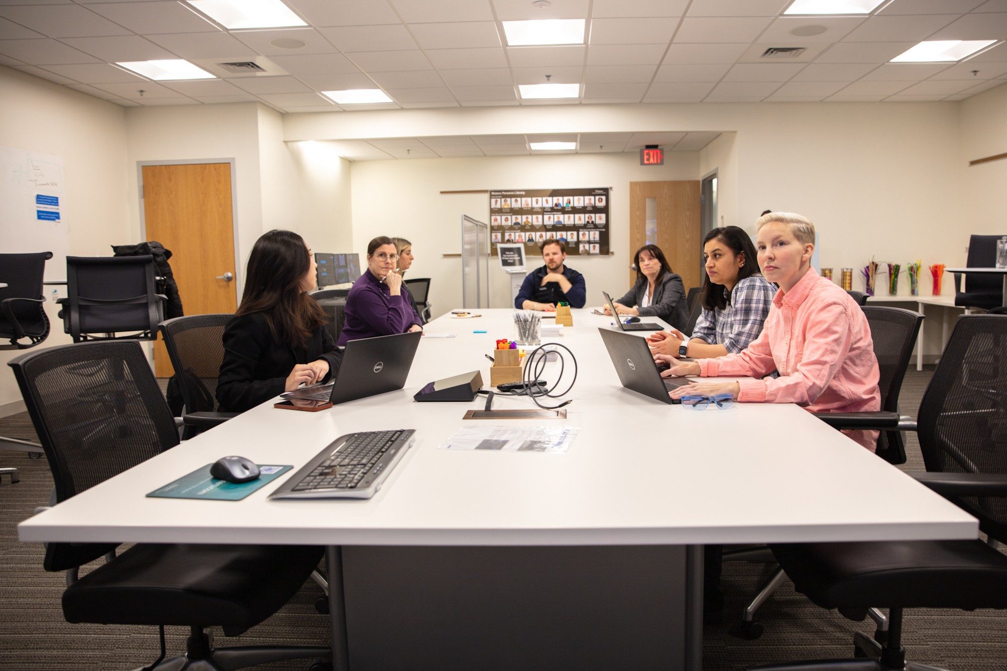 Researchers sit around a long table in the Observation Room