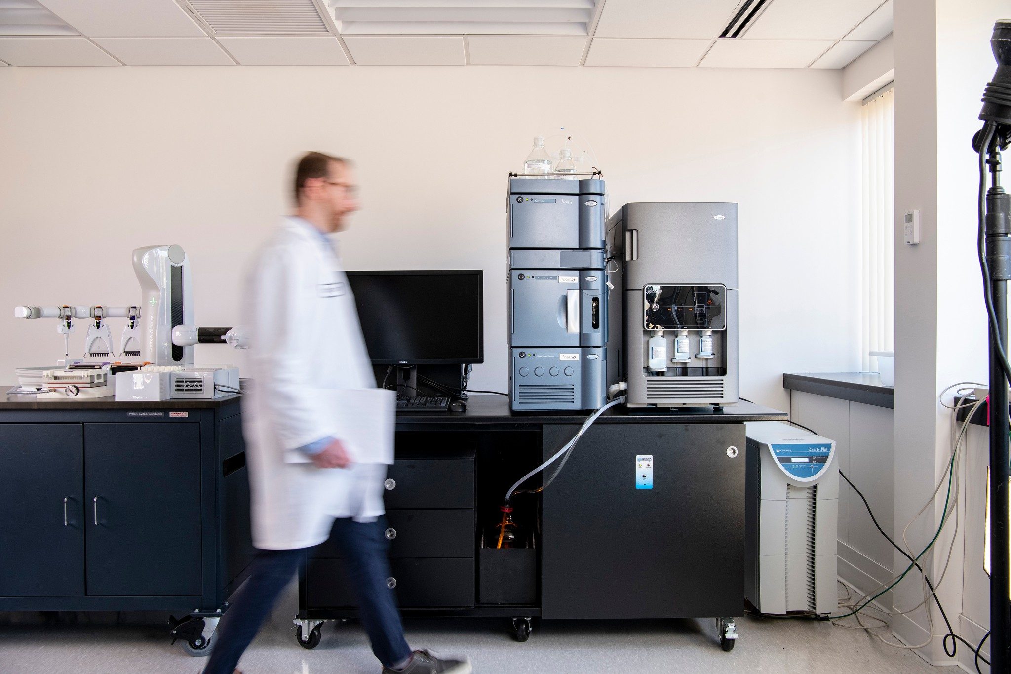 Scientist walking in a laboratory with ACQUITY I-Class, ACQUITY RDa, and Andrew Plus systems