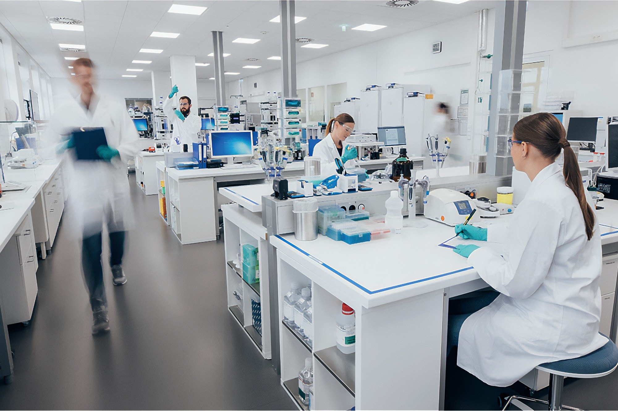 Many scientists working in a busy and bright white laboratory