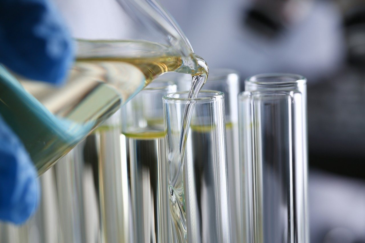 Hand hold yellow petrol liquid in test tube