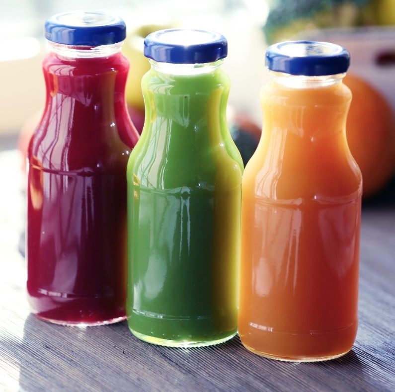 Bottles of juice with fruits and vegetables on table