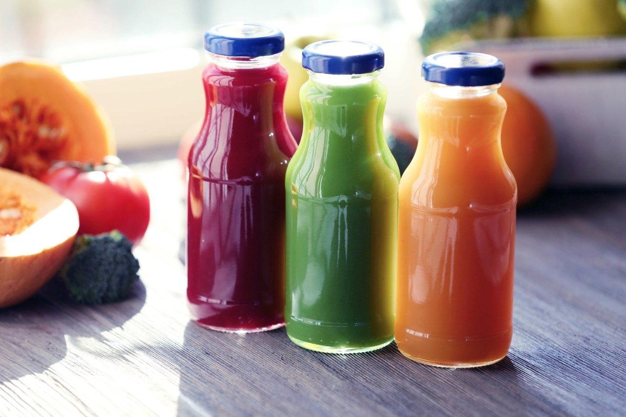 Bottles of juice with fruits and vegetables on table