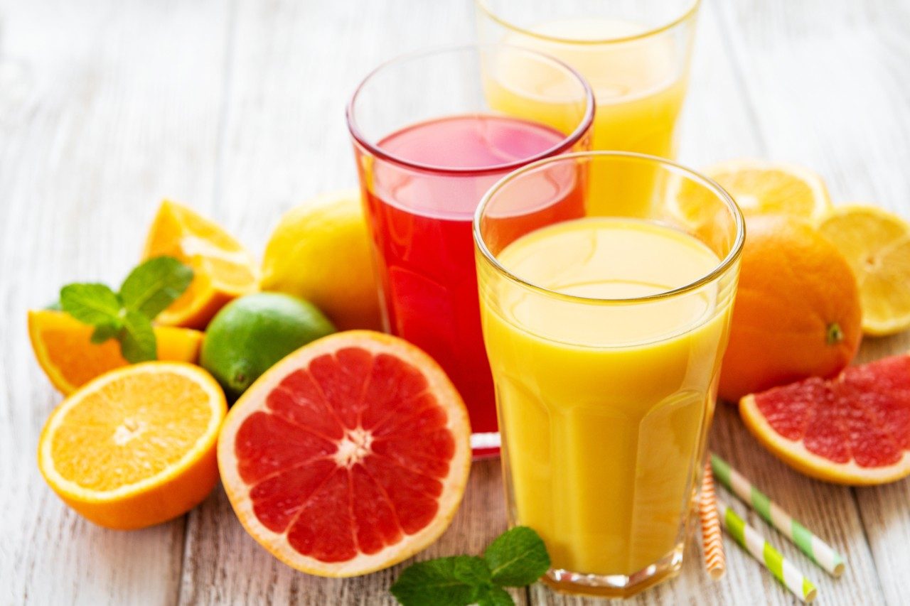 Glasses of juice and citrus fruits on a wooden table