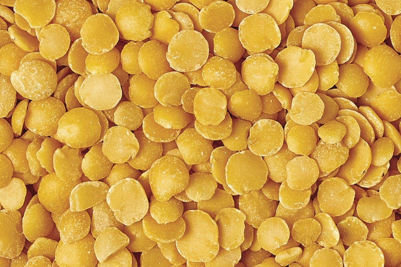 Bowl of yellow split lentil isolated on white background top view