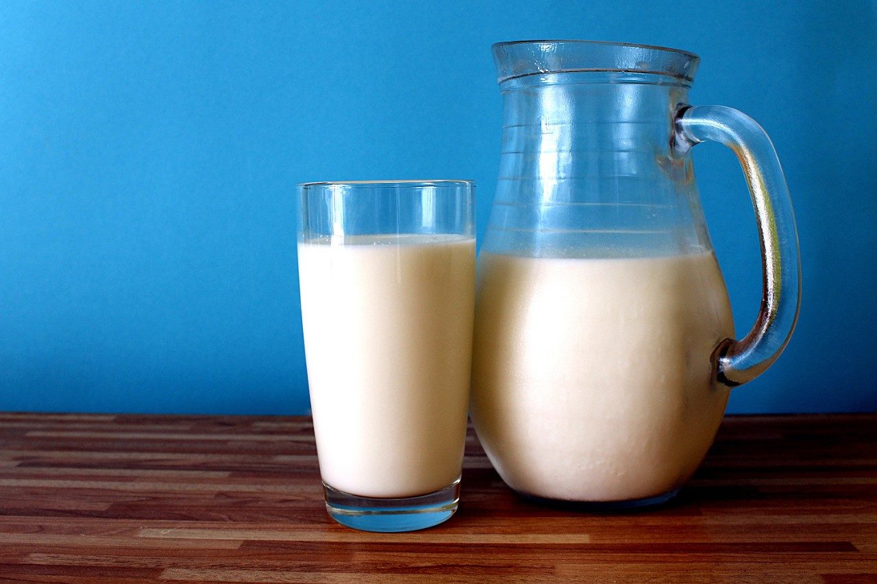 Cold milk in glass and glass jug on wood table