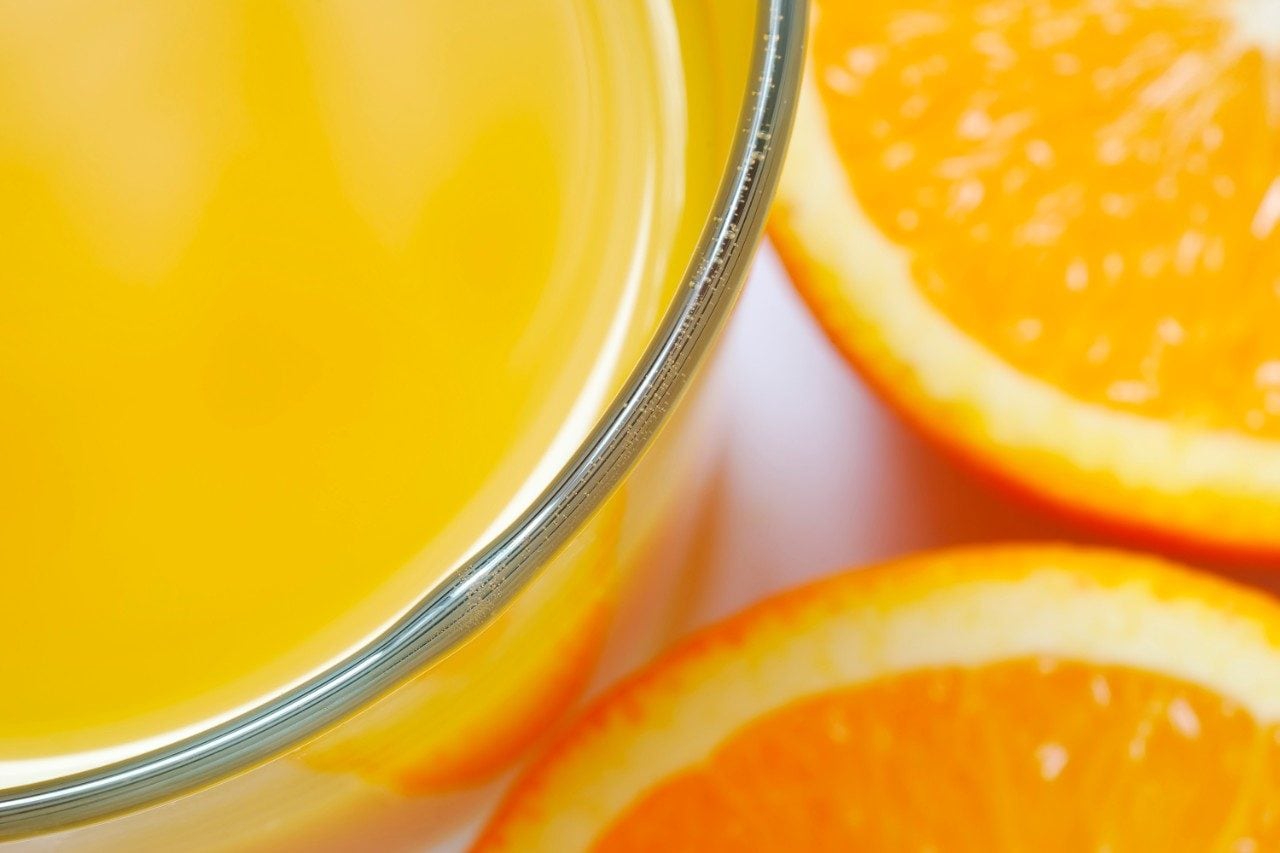 Orange juice in glass with cut oranges