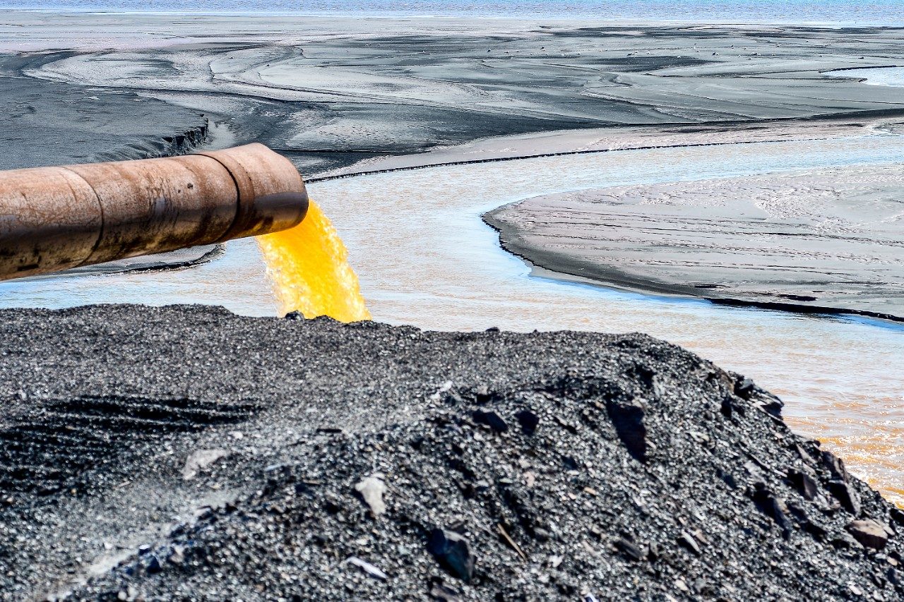 Industrial wastewater discharging from pipe into the water