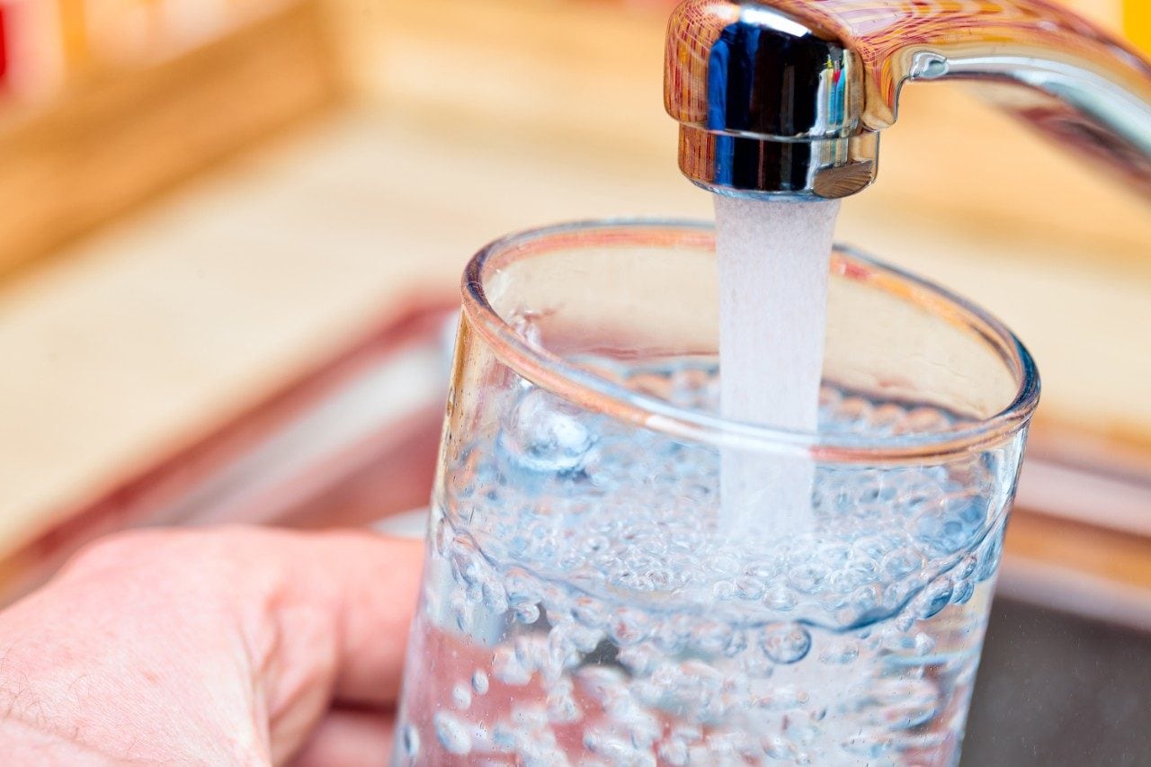 Filling glass with drinking water from kitchen tap