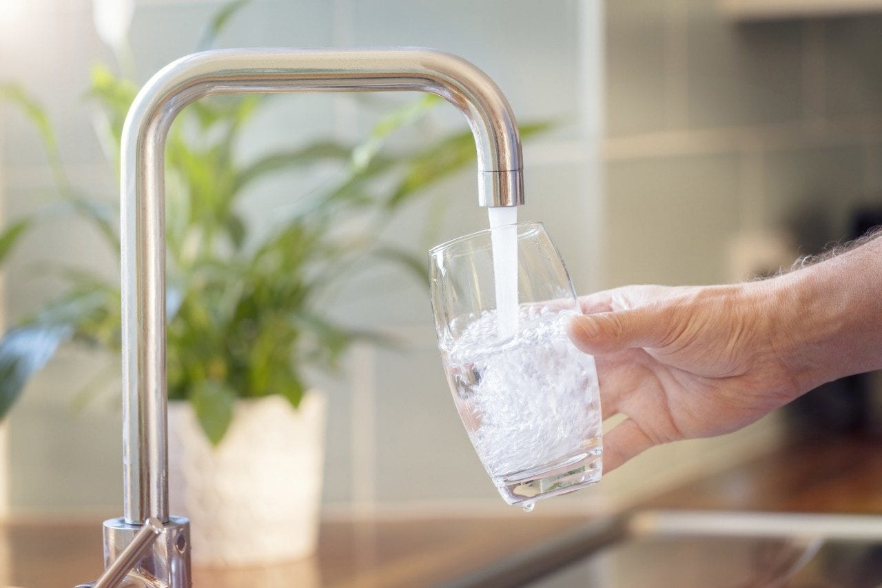 Tap water from kitchen faucet filling up glass