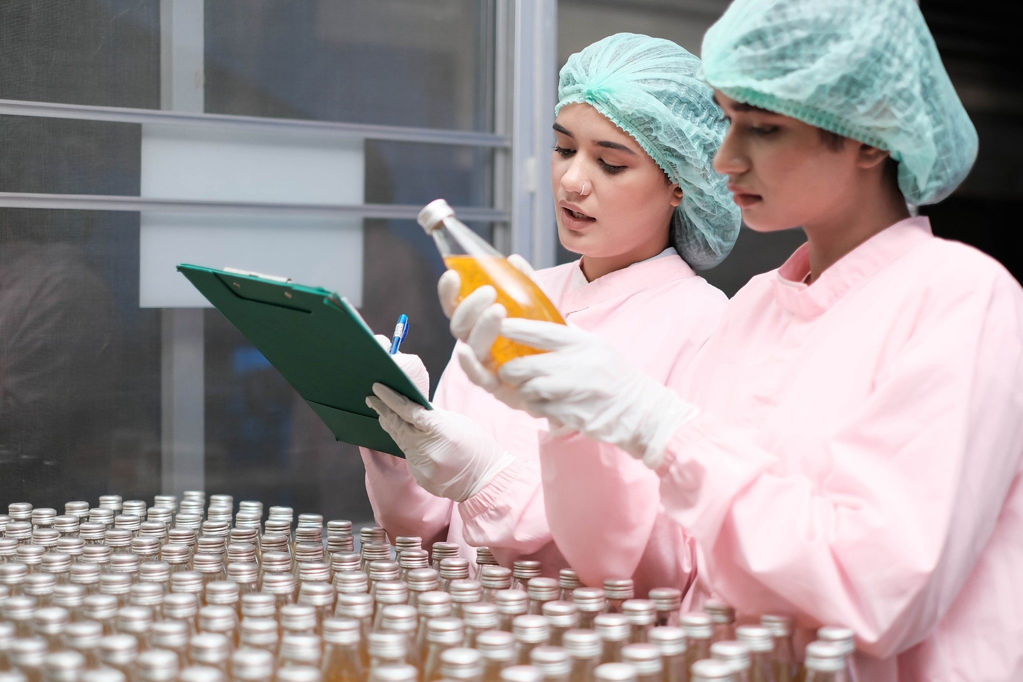 Two factory worker inspecting production line of drink production in factory