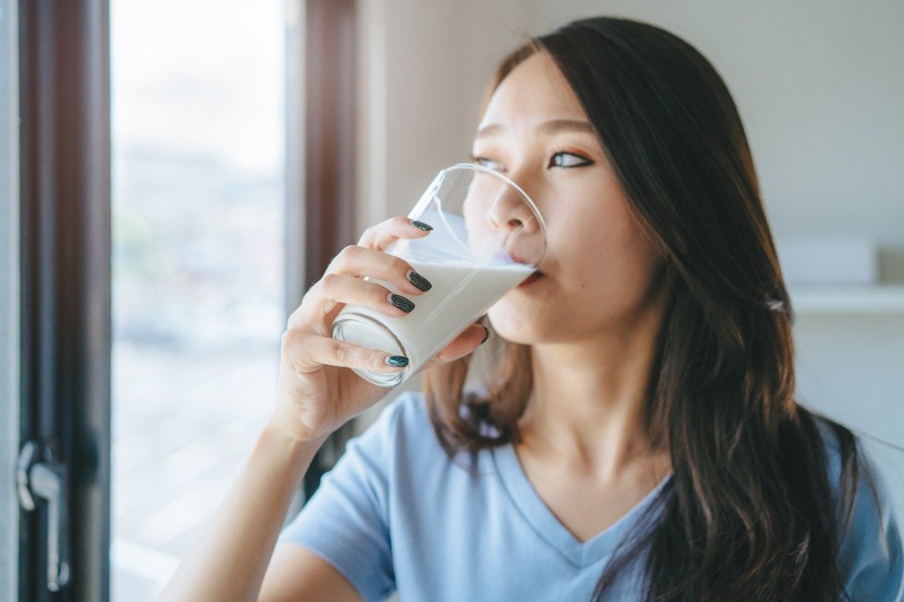 Asiatische Frau trinkt Milch