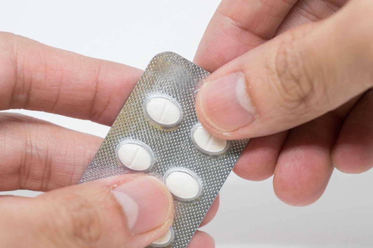 Hand taking allergy pills from blister pack