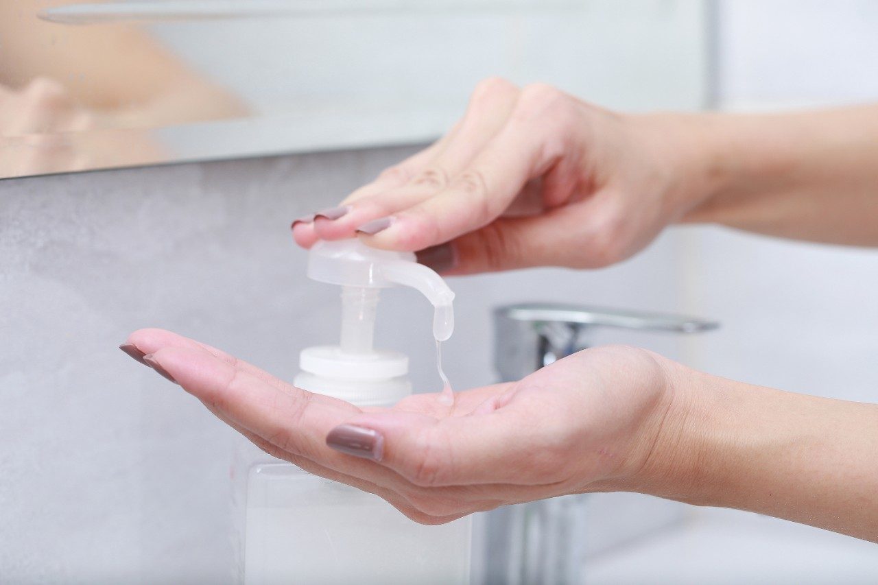 Washing hands with sanitizer gel or antibacterial soap pump dispenser