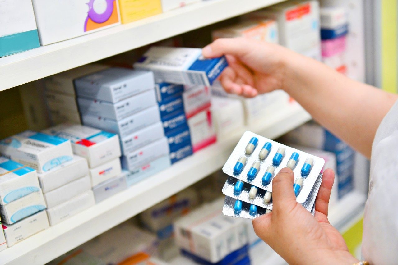 Pharmacist holding antibiotic capsule pack in pharmacy