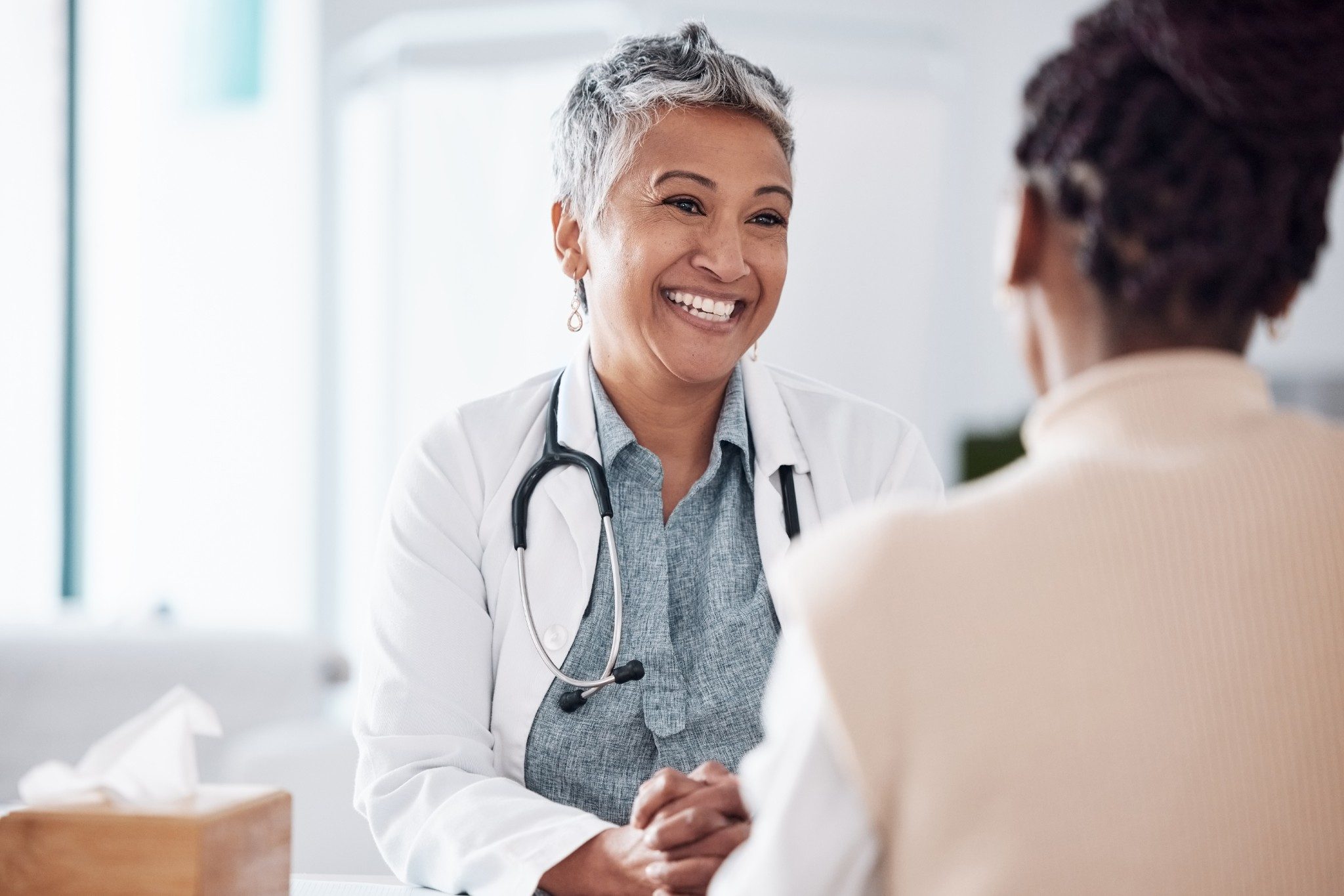 Female doctor happily talking to a patient in a brightly lit room