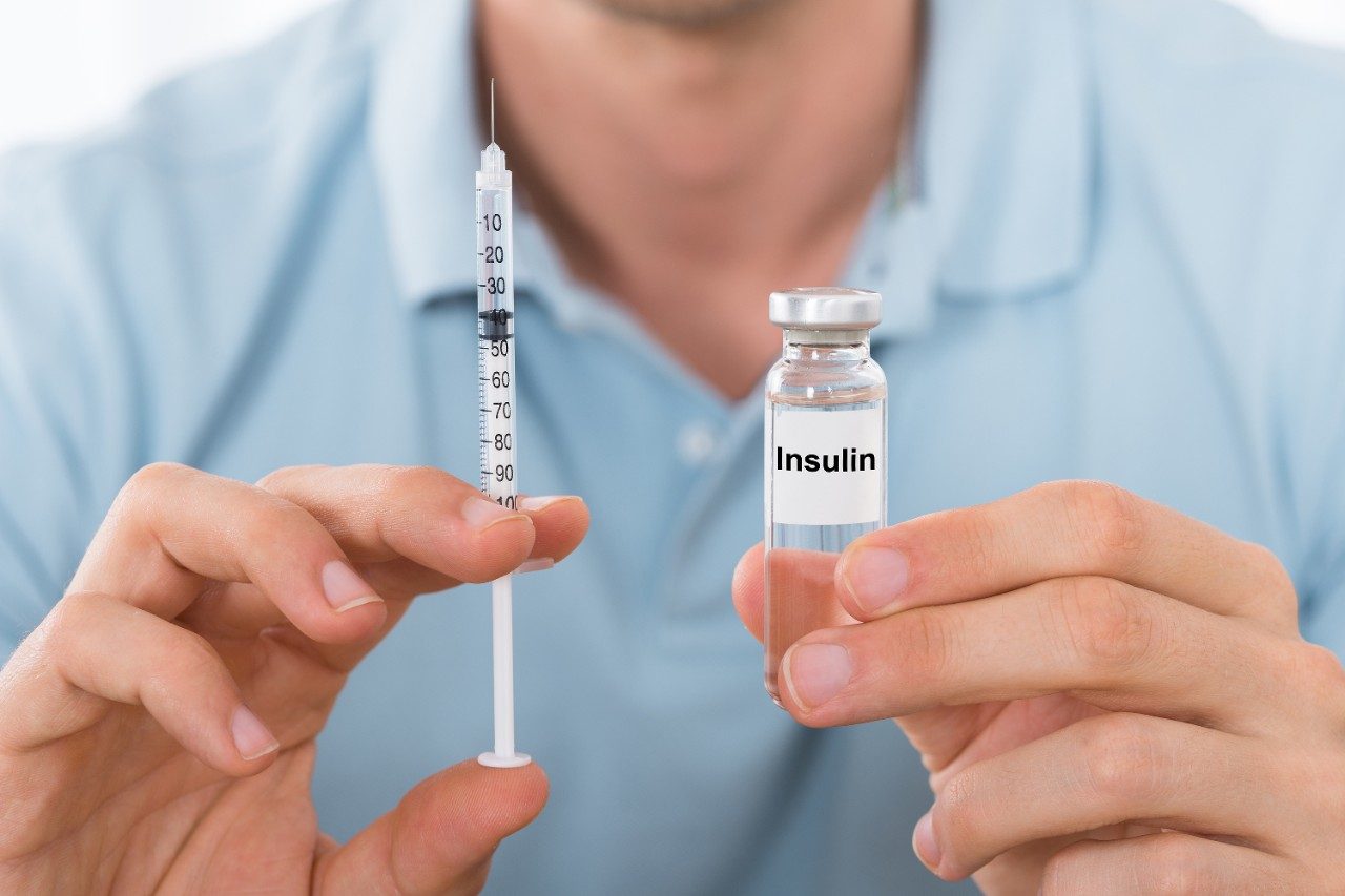 Young man holding insulin and syringe