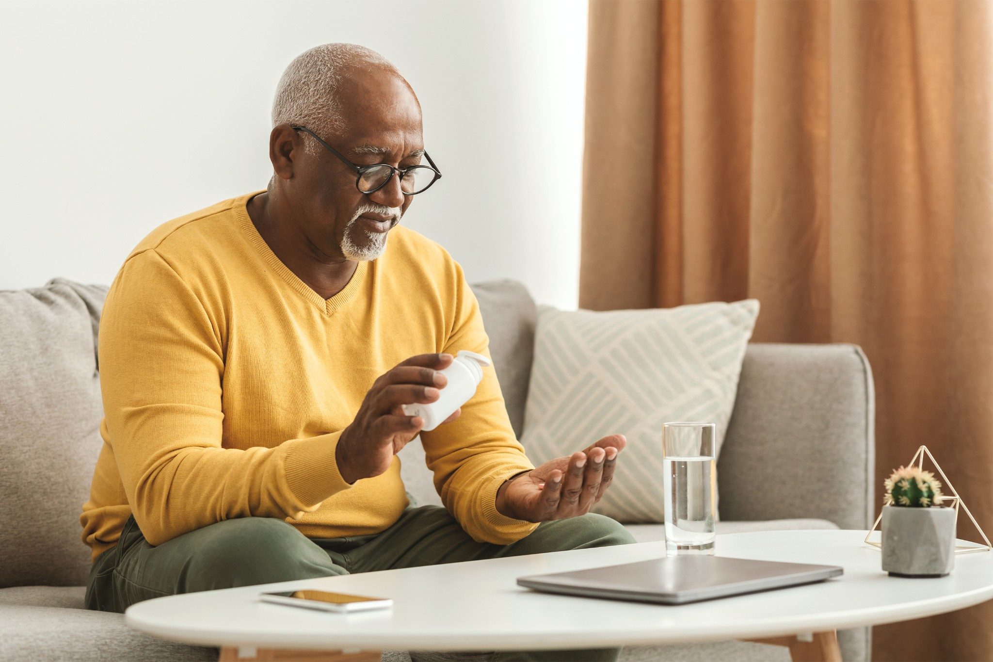 Man sitting on couch taking medication