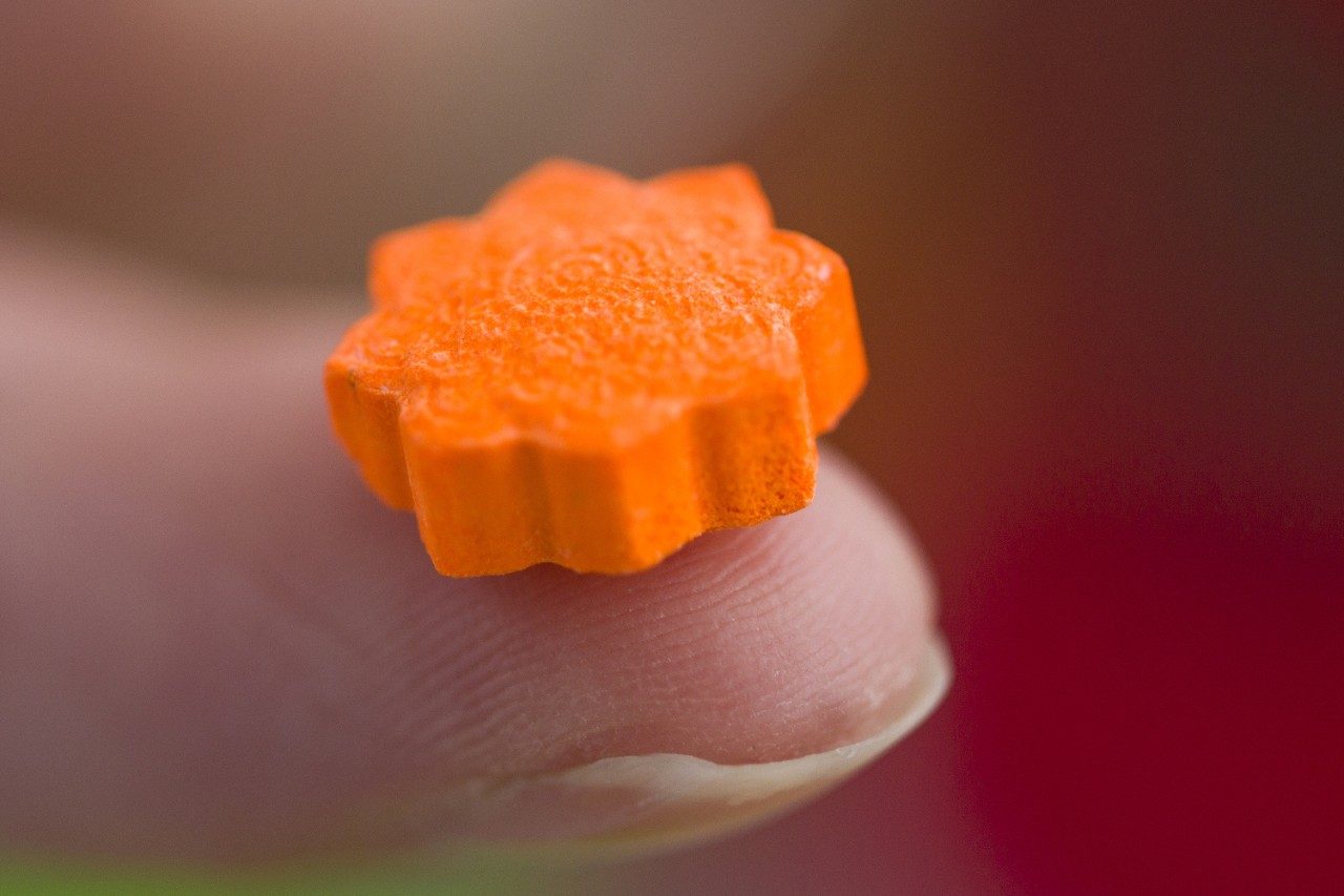 MDMA ecstasy pill on fingertip
