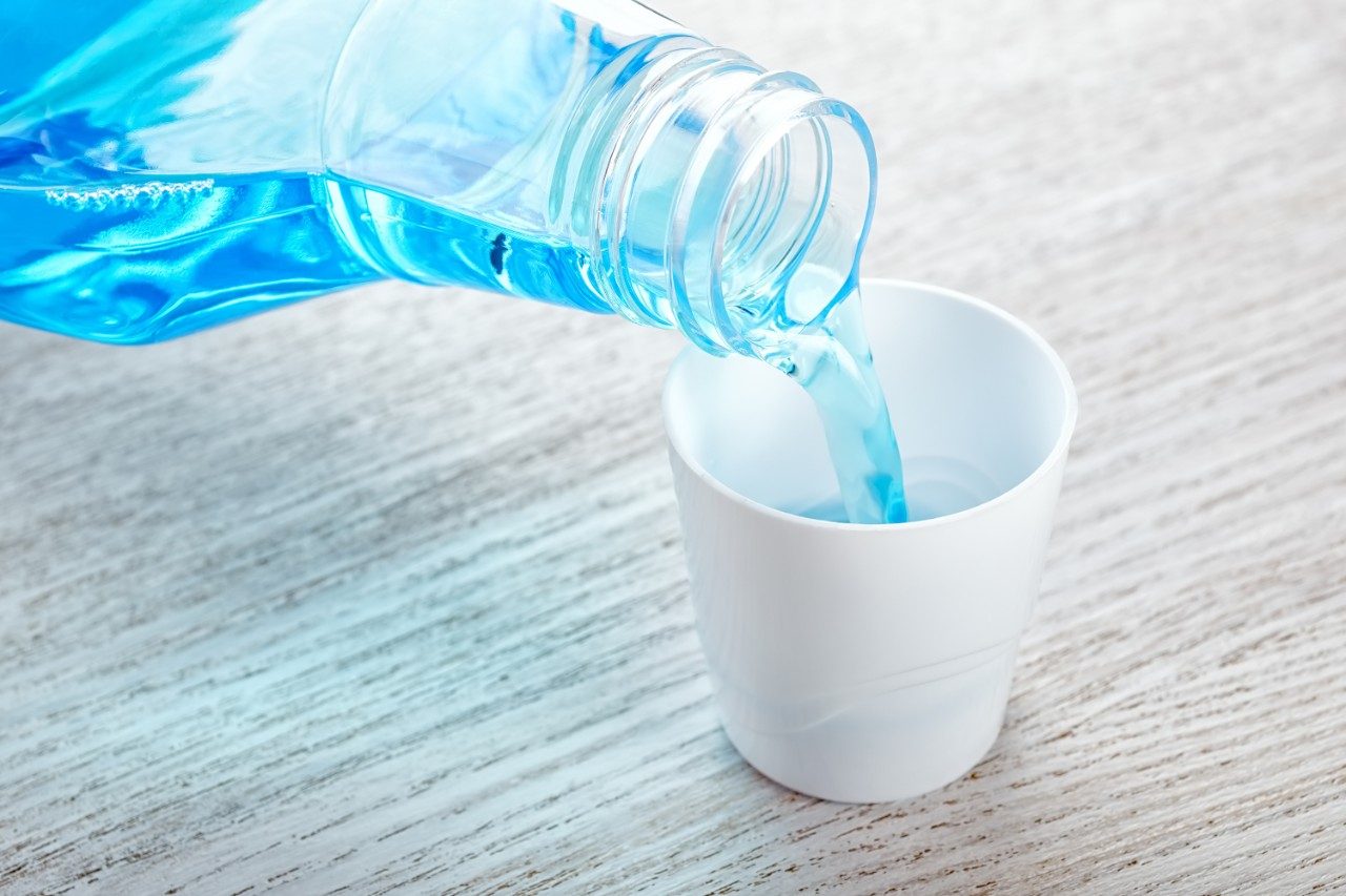 Mouthwash from plastic bottle flowing into cap