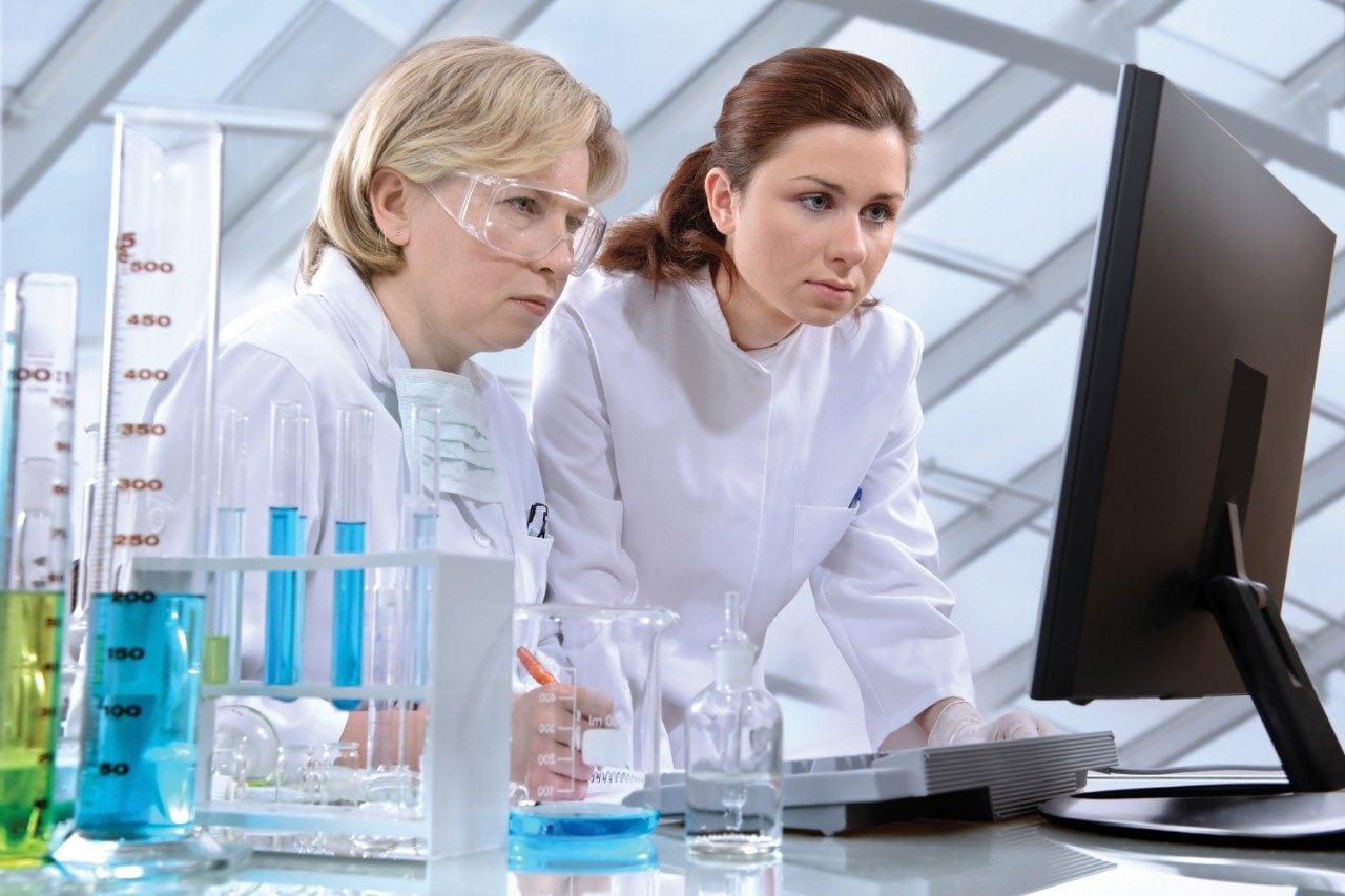 Two female scientists reviewing data on monitor
