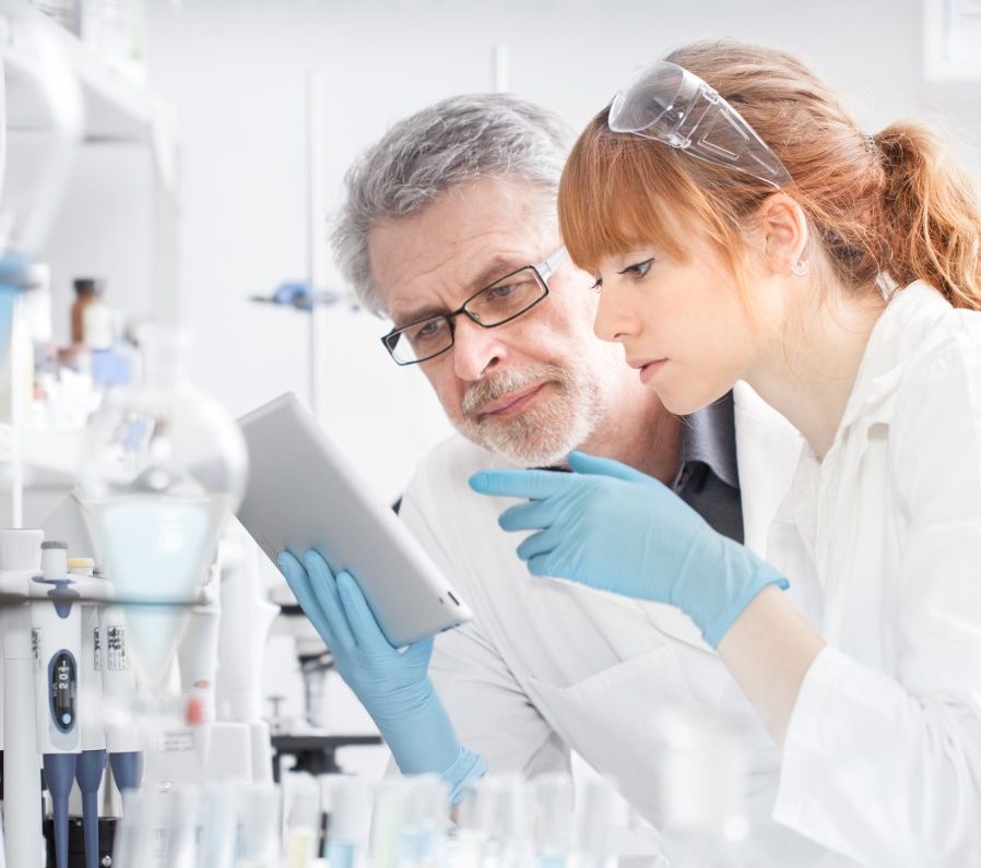 Researchers working in scientific laboratory looking at tablet