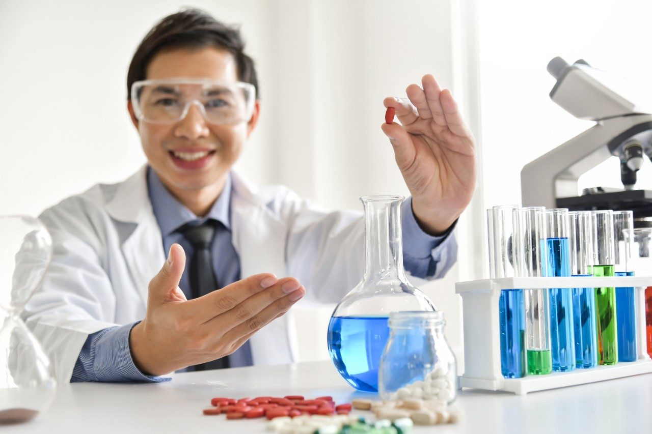 Young male scientist holding a pill