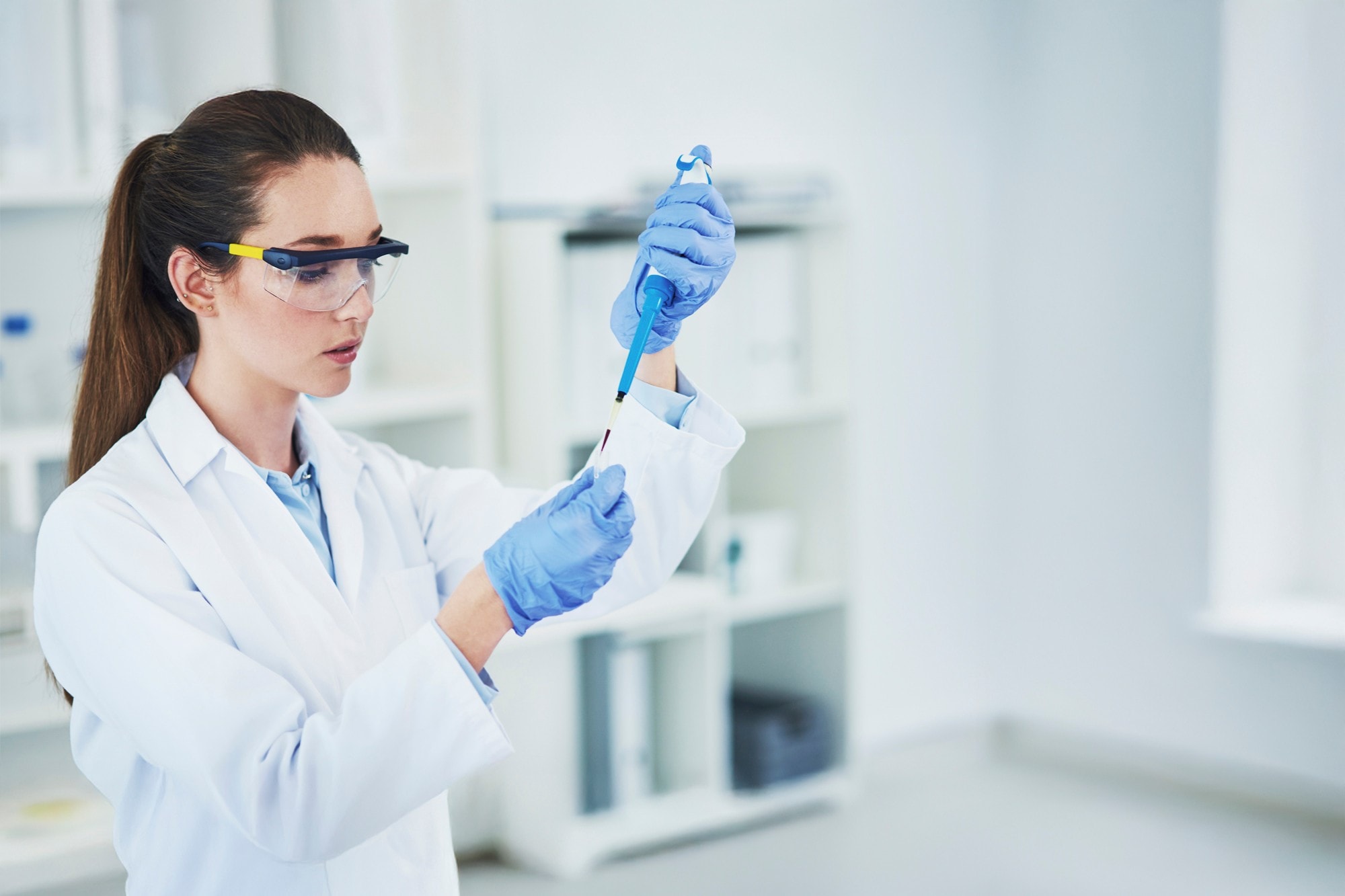 Scientist pipetting in a bright, white lab