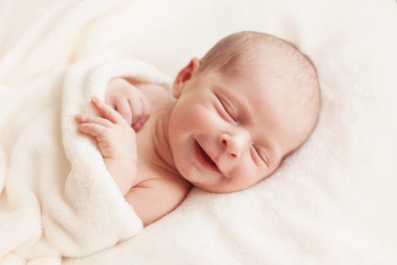 Newborn baby smiling in blanket