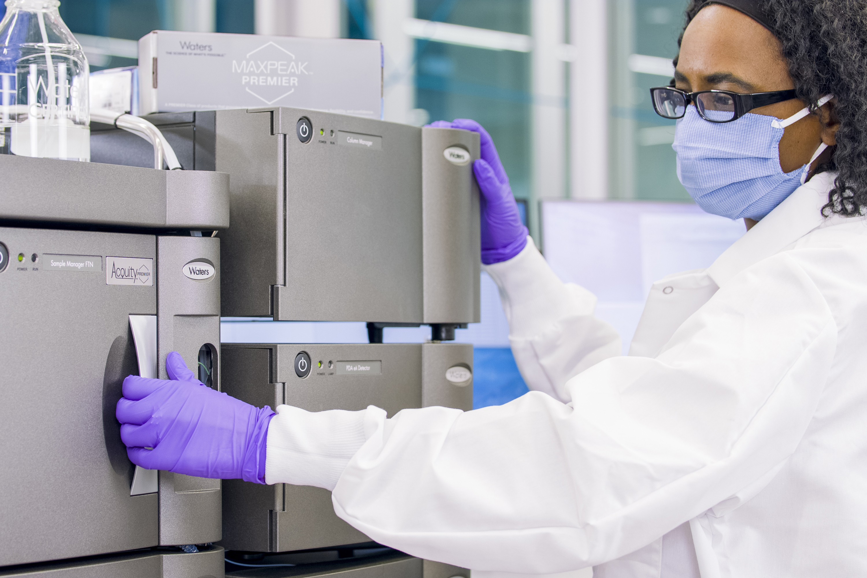 Una ricercatrice del laboratorio apre lo sportello del sistema ACQUITY Premier