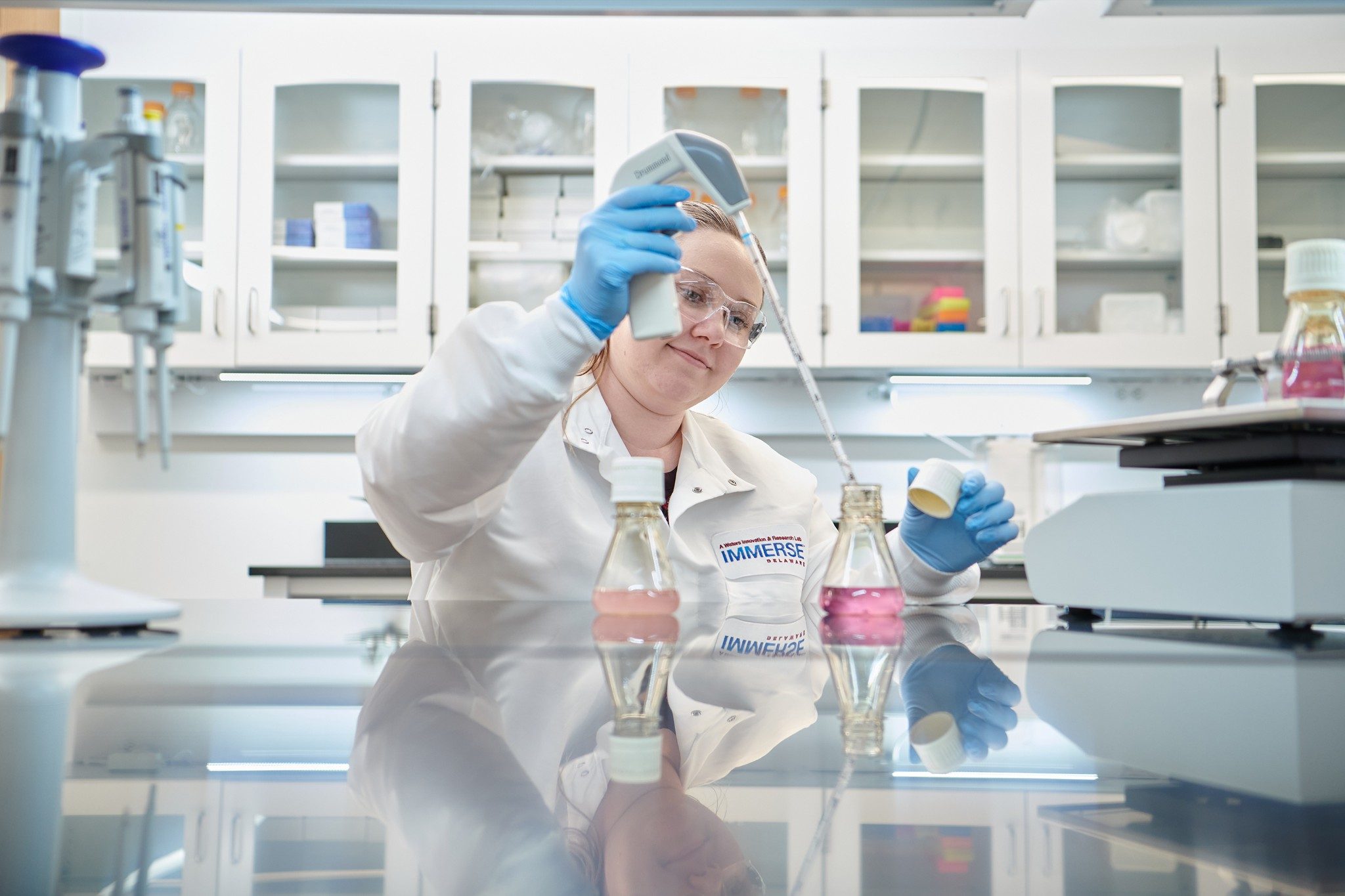 Scienziata del laboratorio Immerse Delaware che utilizza uno strumento di grandi dimensioni per lavorare con un liquido in una boccetta